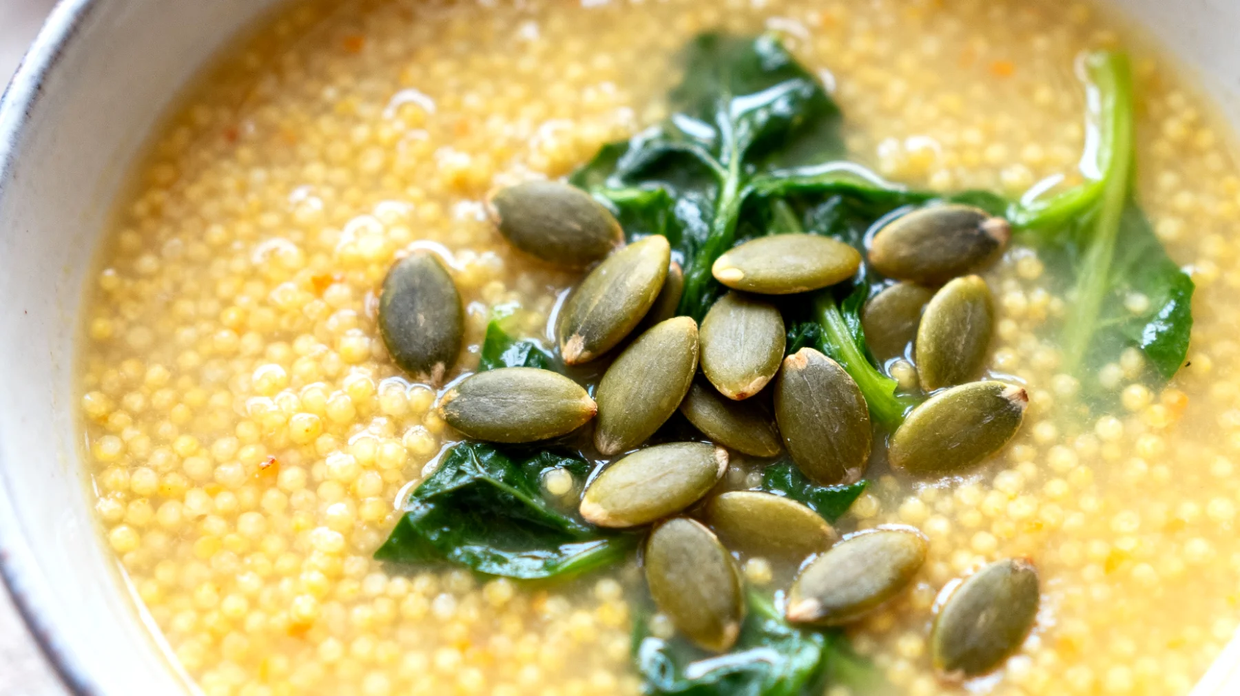 Zuppa di miglio con semi di zucca e verdure a foglia verde"